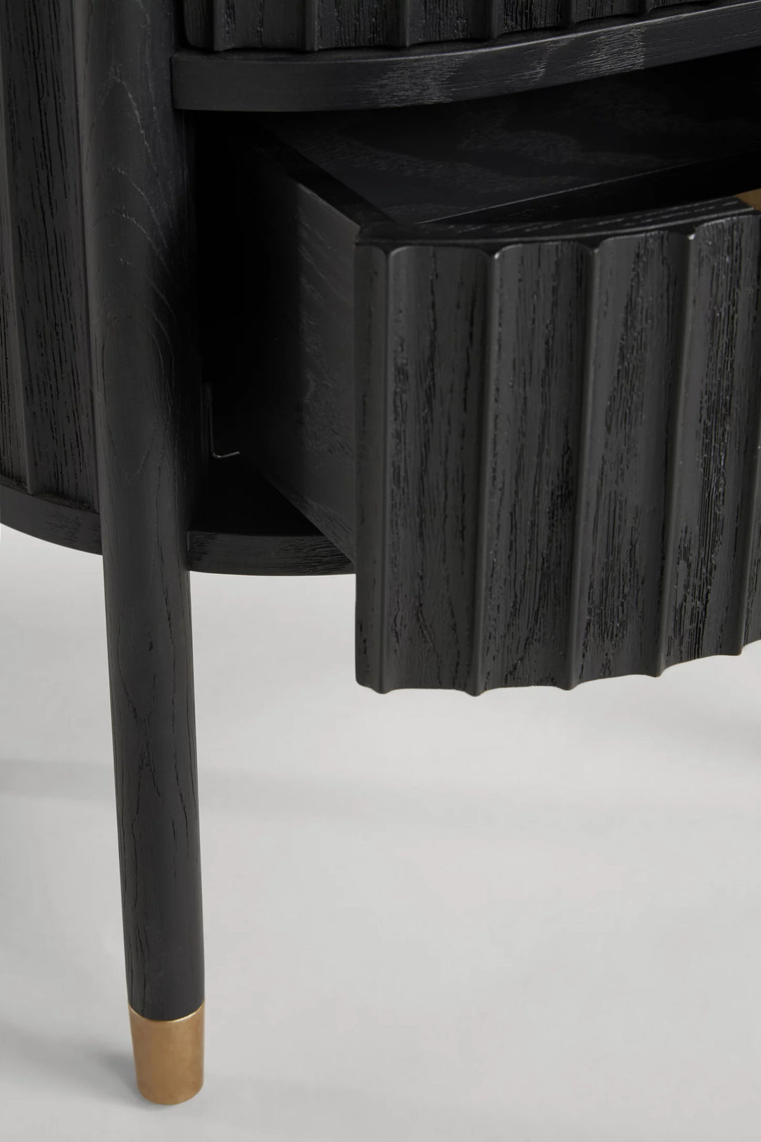 Black wooden side table with a scalloped edge and gold foot on a white background